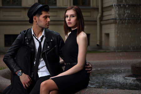 Lovers guy and girl hold hands on the background of a beautiful fountainの写真素材