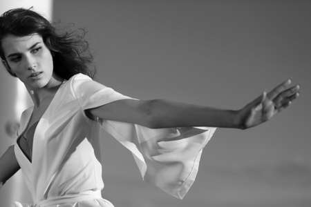 Portrait of a beautiful girl against a blue sky in flowing white clothesの写真素材