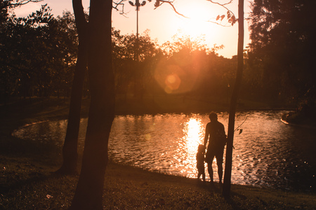 Family of parents dad and daughter children silhouettes at beautiful sunset nature outdoors backgroundの写真素材