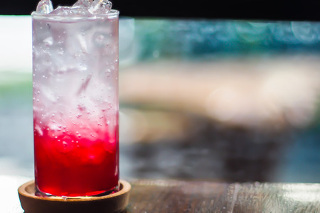 Soda. Red sparkling water with ice in a glass bokeh blur backgroundの写真素材