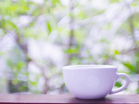 Cup coffee and tea with steam on wood table over mountains city landscape with sunlight. Beauty nature blur green bokeh background. Lifestyle Conceptの写真素材