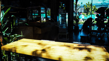 wooden table in front of the blur background with the shadow of tree flower and window, coffee shop,...