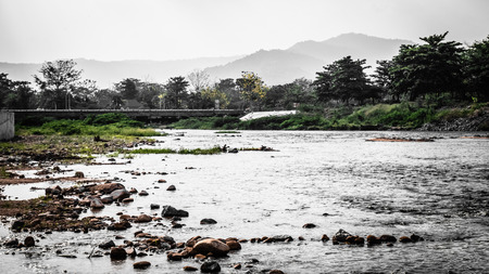 Long bridge across small lake river in the mountain forest in summer. Beautiful scenetic landscapeの写真素材