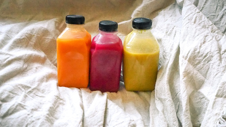 Juice in a bottle on linen background. Natural concept idea. Healthy drink in transparent plastic bottle.の写真素材