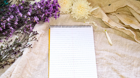Blank paper and flower decoration. Greeting card on a white natural; linen background. Top view. Copy space.の写真素材