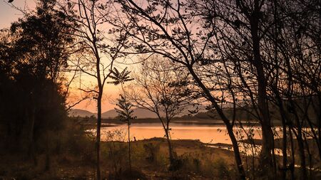 Landscape with orange and purple at sunset  silhouettes of mountains, hills and forest lakeの写真素材