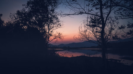Landscape with orange and purple at sunset  silhouettes of mountains, hills and forest lakeの写真素材