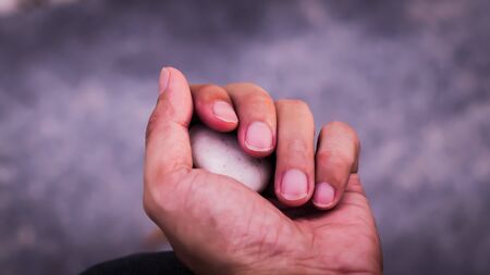 Stone held in hands. Hand hold stone ball in nature. Circular stoneの写真素材