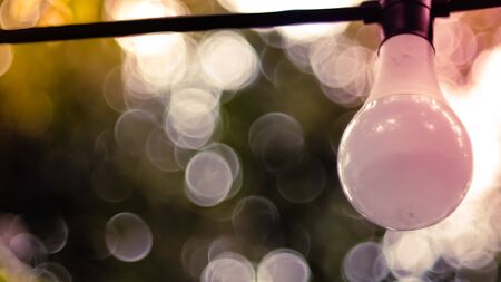 Beautiful retro bulb light lamp decor. Hanging decorative Christmas lights for an outdoor party. Blur bokeh backgroundの写真素材