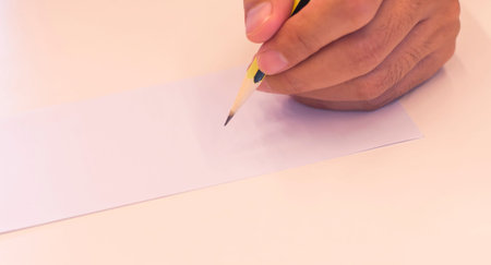 hand holding a pencil isolated on white background . Close Up on a man's hand writing on paper with...