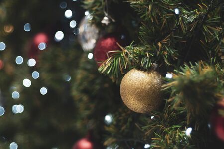 Decorated Christmas tree on blurred background. Christmas decoration. Hanging red balls on pine branches christmas tree garland and ornaments over abstract bokeh background with copy spaceの写真素材