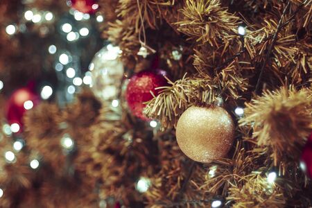 Decorated Christmas tree on blurred background. Christmas decoration. Hanging red balls on pine branches christmas tree garland and ornaments over abstract bokeh background with copy spaceの写真素材