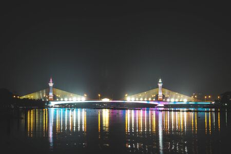 view of night scenery of city in Thailand  with beautiful reflections of skyscrapers and bridges by riverside in twilight. Cityscape view of bridge crosses the Chao Phraya Riverの素材 [FY310136561496]