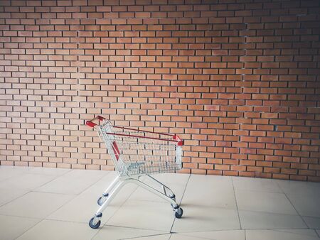 Empty shopping cart near brick wall . Shopping supermarket cart. Shopping time concept ideaの写真素材