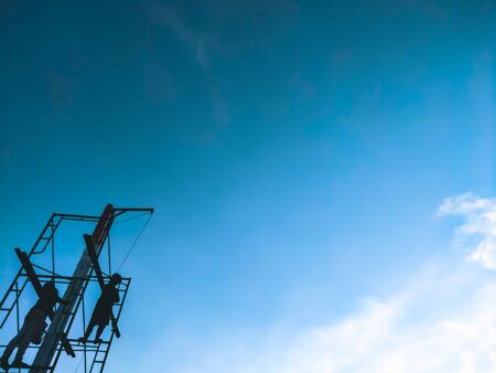 Men standing high up on a makeshift scaffold tower. the worker rebuild an exterior section of a house under renovation and construction. blue sky backgroundの写真素材