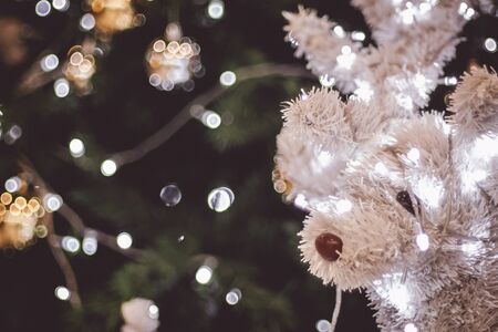 funny reindeer with lights tangled in antlers . Decorated Christmas tree on blurred background.  New Year holidays background.の写真素材