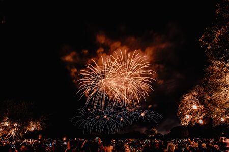 Group of people watching fireworks and using cellphones to record event. People capturing a fireworks shows with their mobile phone. Colorful fireworks celebration and the night sky backgroundの写真素材
