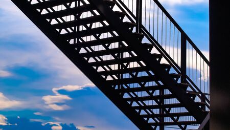 side view of outside metal staircase or fire exit stair with sheet  against blue sky. moving up concept ideaの写真素材