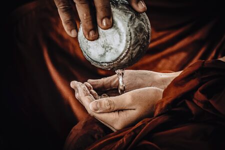 Close up hands .sprinkling scented water on monk's hand .pouring water traditional in Thai New year. Traditional beauty of Thai .The traditional Thai New Year or Songkranの写真素材