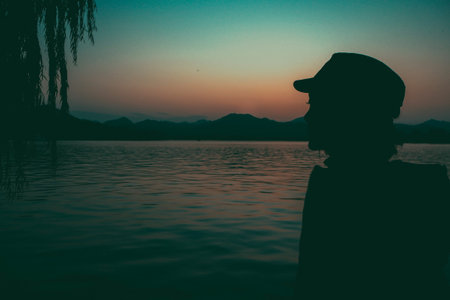 Dusk Woman Lake Silhouette against Orange Sky mountains background.  Free woman enjoying freedom...