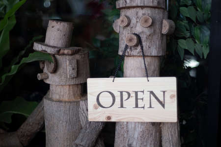 Open Sign Hanging on wooden doll in front of entrance door for decoration cafe restuarant.の写真素材