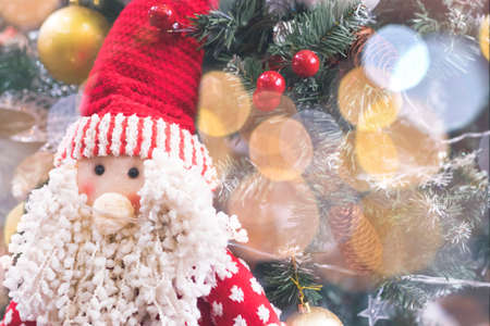 Happy santa claus decoration on the table with christmas tree bokeh on backgroundの写真素材
