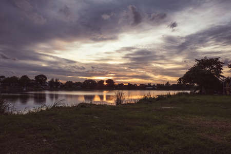 Dramatic  sunset landscape with orange sky, silhouettes of  trees and lake. sky of lake landscape at sunsetの写真素材