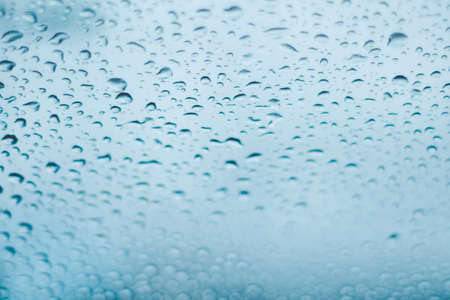 Raindrops on the window. Water droplets on glass. Blue toneの写真素材