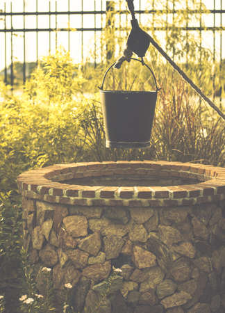 bucket scoop water Vintage image of countryside garden with water well in rustic villageの写真素材
