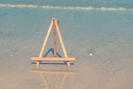 Wooden Easel photo stand tripod for photo with sea on backgroundの写真素材