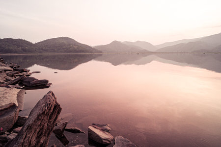 Panorama scenic of mountain lake with perfect reflection at sunrise. beautiful mountain range landscape with pink pastel sky with hills on background and reflected in water. Nature lake landscapeの写真素材