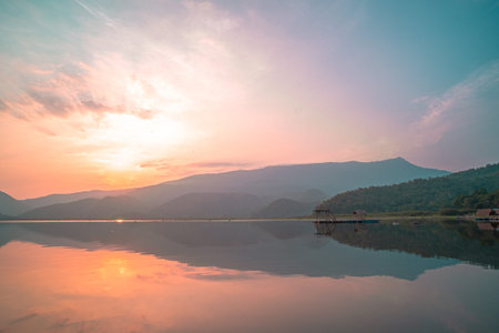 Panorama scenic of mountain lake with perfect reflection at sunrise. beautiful mountain range landscape with pink pastel sky with hills on background and reflected in water. Nature lake landscapeの写真素材