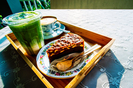 cake with hot coffee and Green tea Latte on table in cafeの写真素材