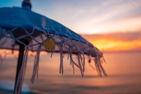 Beautiful detailed photo of beach asian umbrella on backgrond of amazing scarlet sunset in Baliの写真素材