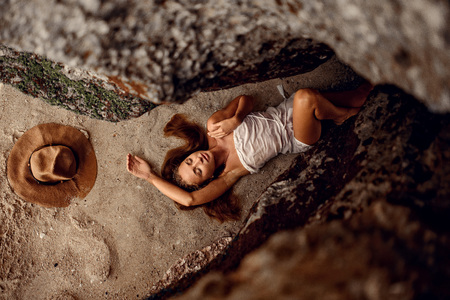 fashion photo of beautiful woman with brunette hair in white  dress and hat posing in cave on the tropic beach in Baliの写真素材
