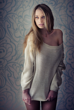 fashion photo of beautiful woman with long blonde hair in knitted sweater posing on light backgrounde in studioの写真素材