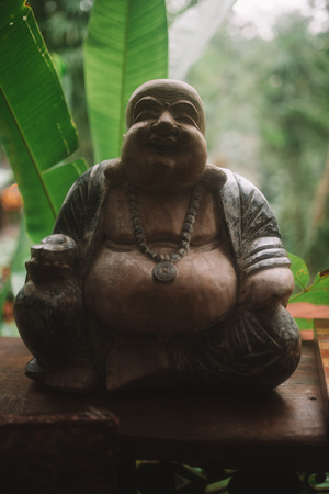 Photo of wood statue of the god of abundance Hotey with tropical forest on background in Baliの写真素材
