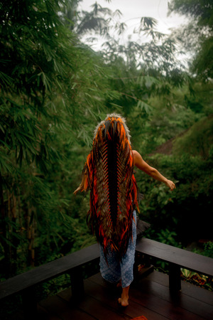 fashion photo of beautiful woman in long bright indian roach and blue boho clothes posing on the wood verande in tropical Jungle background in Baliの写真素材
