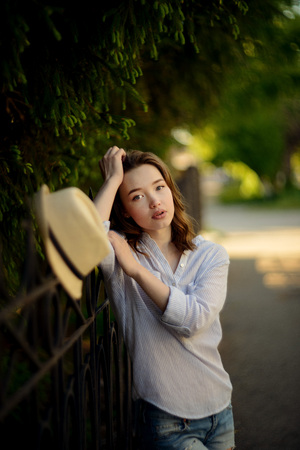 fashion outdoor summer photo of beautiful woman with brunette hair in casual clothes with beige hat walking on a sunny dayの写真素材