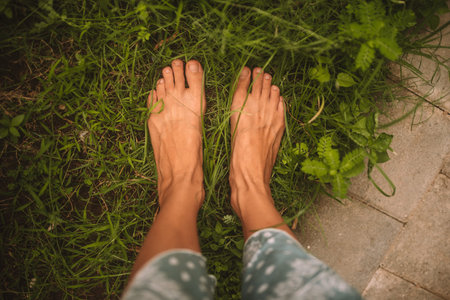 Beautiful photo of tanned foots stay in green grass in tropical garden in Bali