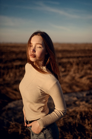 fashion outdoor winter photo of beautiful woman with brunette hair in casual clothes posing in sun rays on background of awesome landscapeの写真素材