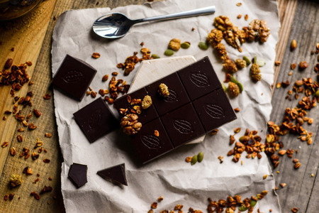 beautiful food photo of tasty dark chocolate with homemade granola on the rustic background wood tableの写真素材
