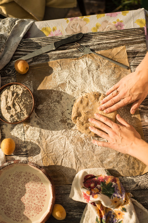 warm light photo of outside a woman in gentle sundress cooking a sweet pie with fresh apricots on a sunny summer dayの写真素材