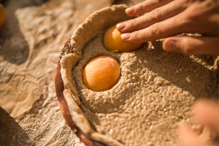 warm light photo of outside a woman in gentle sundress cooking a sweet pie with fresh apricots on a sunny summer dayの写真素材