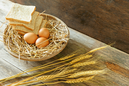 Eggs and breads in the basket with wooden backgroundの写真素材