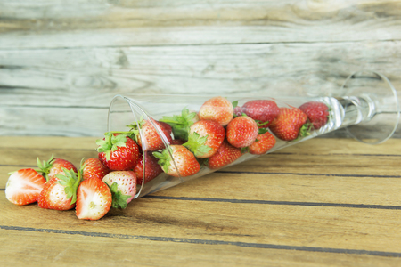 Strawberry berries in a glass on a wooden table.の写真素材