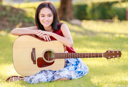 Girl with guitar in the grass.