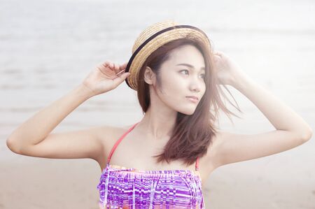 Young woman in a hat looking on the beach with vintageの写真素材