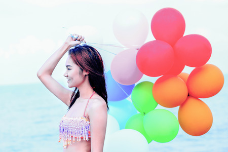 girl with colorful balloons on the beach with vintageの写真素材