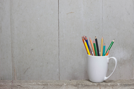 broken color pencils on White Mug lay on the cement.の写真素材
